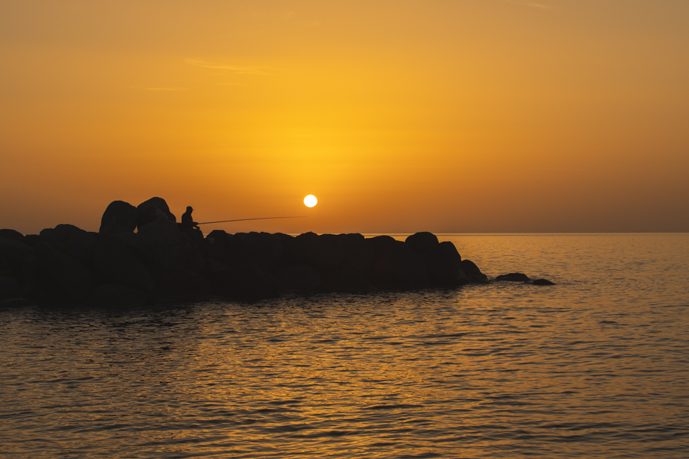 Griekse zonsopkomst Kamari visser op de rotsen bij de zee Canon 5DMark door Wilma Fotografeert